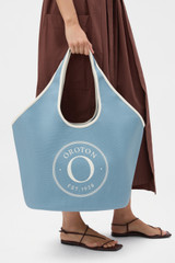 Profile view of model wearing the Oroton Kaia Crescent Shopper Tote in Sky Blue/Cream and Canvas material for Women .