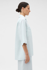 Profile view of model wearing the Oroton Tab Detail Tunic in Ice Blue and 100% heavy weight linen fabric for Women .
