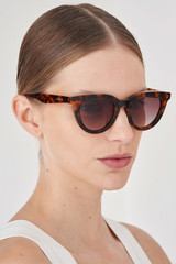 Profile view of model wearing the Oroton Heidi Sunglasses in Signature Tort and Premium acetate material for Women .