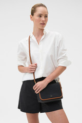 Profile view of model wearing the Oroton Laura Flap Over Crossbody in Black/Cognac and Premium pebble leather for Women .