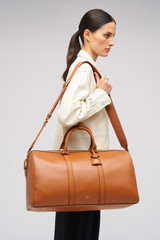 Profile view of model wearing the Oroton Wanderer Weekender in Amber and Premium smooth leather for Women .