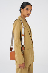 Profile view of model wearing the Oroton Heather Long Light Gold Webbing Strap in Cognac/Natural and Polyester webbing strap for Women .
