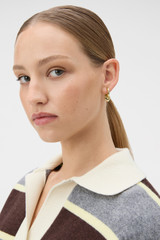 Profile view of model wearing the Oroton Heart Charm Hoop Earrings in Gold and Premium brass material for Women .