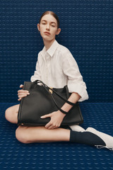 Profile view of model wearing the Oroton Mille Work Tote in Black and Premium pebble leather for Women .