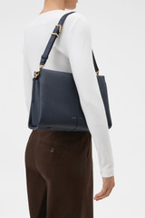 Profile view of model wearing the Oroton Dorit Day Bag in Dark Navy and Premium pebble leather for Women .