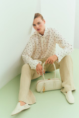 Profile view of model wearing the Oroton Graphic Spot Tie Neck Shirt in Cream and 100% Silk for Women .