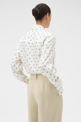 Profile view of model wearing the Oroton Graphic Spot Tie Neck Shirt in Cream and 100% Silk for Women .