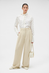 Profile view of model wearing the Oroton Graphic Spot Tie Neck Shirt in Cream and 100% Silk for Women .