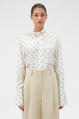 Profile view of model wearing the Oroton Graphic Spot Tie Neck Shirt in Cream and 100% Silk for Women .