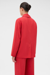Profile view of model wearing the Oroton Soft Double Breasted Blazer in Ribbon Red and 77% viscose and 23% polyamide blend fabric for Women .