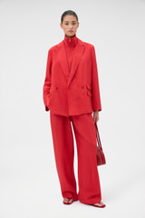 Profile view of model wearing the Oroton Soft Double Breasted Blazer in Ribbon Red and 77% viscose and 23% polyamide blend fabric for Women .