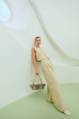 Profile view of model wearing the Oroton Pleat Detail Pant in Almond Creme and 72% viscose and 28% linen blend fabric for Women