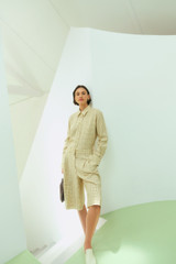Profile view of model wearing the Oroton Pleat Check Short in Pale Lemon/Chocolate and 87% viscose and 13% polyester blend fabric for Women .