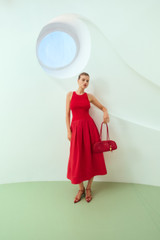 Profile view of model wearing the Oroton Knit Bodice Midi Dress in Ribbon Red and Knit: 100% cotton; Skirt: 77% viscose, 23% polyester for Women .