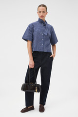 Profile view of model wearing the Oroton Check Tie Neck Shirt in North Sea and 100% cotton fabric for Women .