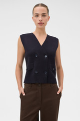Profile view of model wearing the Oroton Milano Knit Vest in North Sea and 93% mercerised cotton yarn, 6% nylon, and 1% elastane blend fabric for Women .