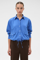 Profile view of model wearing the Oroton Poplin Drawstring Shirt in French Blue and 100% cotton fabric for Women .