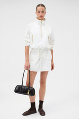 Profile view of model wearing the Oroton Zip Detail Anorak Dress in Antique White and 100% cotton fabric for Women .