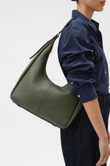 Profile view of model wearing the Oroton Dorit Hobo Bag in Olive and Premium pebble leather for Women .