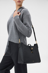 Profile view of model wearing the Oroton Dylan Large Bucket in Black and Premium pebble leather for Women .