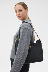 Profile view of model wearing the Oroton Dylan Large Bucket in Black and Premium pebble leather for Women .
