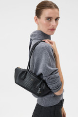 Profile view of model wearing the Oroton Breeze Texture Baguette in Black Snake and Premium embossed leather for Women .