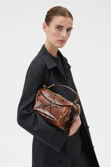 Profile view of model wearing the Oroton Mica Bowler in Copper Snake and Premium pebble grain leather for Women .