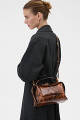 Profile view of model wearing the Oroton Mica Bowler in Copper Snake and Premium pebble grain leather for Women .