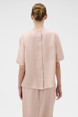 Profile view of model wearing the Oroton Ribbon Trim Top in Rose Tint and 100% silk twill fabric for Women .