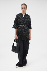Profile view of model wearing the Oroton Harvey Signature Reversible Poncho in Black/Charcoal and 50% acrylic and 50% wool blend fabric for Women .