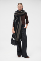 Profile view of model wearing the Oroton Heather Light Weight Wool Scarf in Black/Charcoal and 50% acrylic and 50% wool blend fabric for Women .