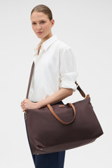 Profile view of model wearing the Oroton Lilly Nylon Weekender Tote in Burnt Umber/Cognac and Nylon fabric material for Women .