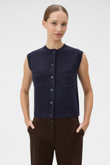 Profile view of model wearing the Oroton Knit Detail Vest in North Sea and 100% superfine wool fabric for Women .