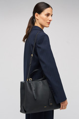 Profile view of model wearing the Oroton Margot Large Day Bag in Black and Premium pebble leather for Women .