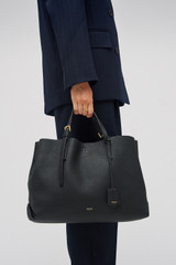 Profile view of model wearing the Oroton Margot Large Day Bag in Black and Premium pebble leather for Women .