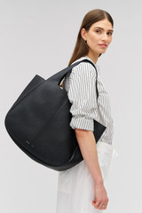Profile view of model wearing the Oroton Emilia Large Tote in Black and Premium pebble leather for Women .
