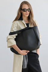 Profile view of model wearing the Oroton Emilia Large Tote in Black and Premium pebble leather for Women .