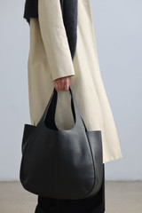 Profile view of model wearing the Oroton Emilia Large Tote in Black and Premium pebble leather for Women .