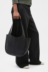 Profile view of model wearing the Oroton Emilia Tote in Black and Premium pebble leather for Women .