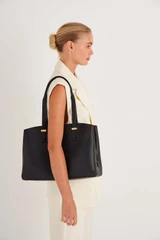 Profile view of model wearing the Oroton Anika 13" Day Bag in Black and Pebble leather for Women .