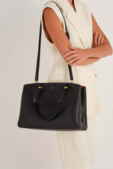 Profile view of model wearing the Oroton Anika 13" Day Bag in Black and Pebble leather for Women .