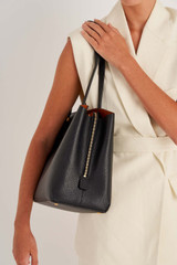 Profile view of model wearing the Oroton Anika 13" Day Bag in Black and Pebble leather for Women .