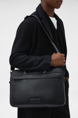 Profile view of model wearing the Oroton Ethan Pebble 15" Griptop in Black and Premium pebble leather for Men .