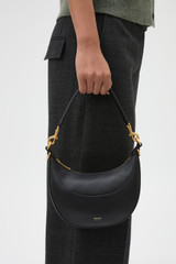 Profile view of model wearing the Oroton Florence Small Shoulder Bag in Black and Premium smooth leather for Women .