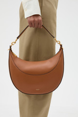 Profile view of model wearing the Oroton Florence Medium Hobo in Cognac and Smooth leather material for Women .