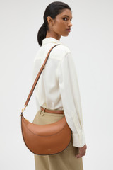 Profile view of model wearing the Oroton Florence Medium Hobo in Cognac and Smooth leather material for Women .