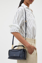 Profile view of model wearing the Oroton Mica Mini Bowler in North Sea and Premium pebble leather for Women .