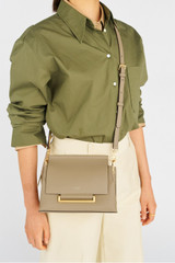 Profile view of model wearing the Oroton Elm Small Satchel in Mushroom and Smooth Pebble Leather for Women .