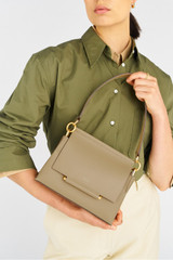 Profile view of model wearing the Oroton Elm Small Satchel in Mushroom and Smooth Pebble Leather for Women .