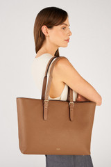 Profile view of model wearing the Oroton Dylan Large Tote in Tan and Main body crafted from 100% pebble leather for Women .
